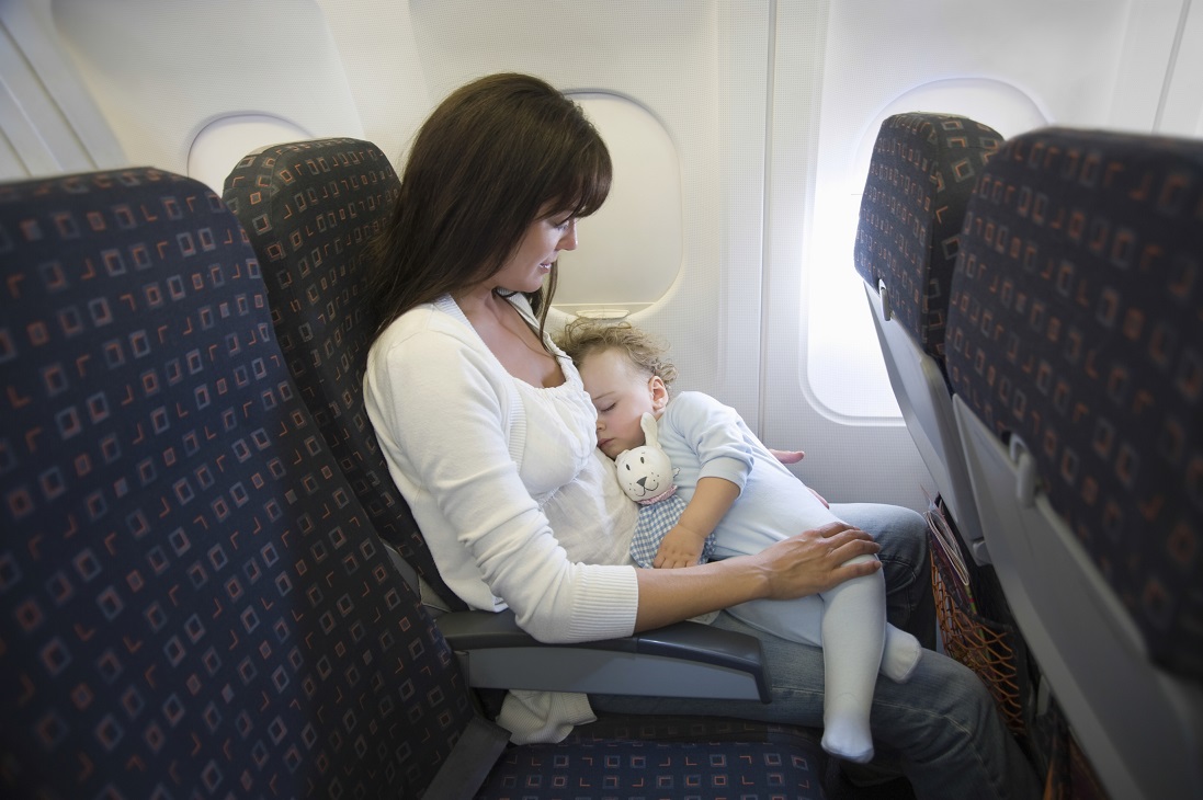 Baby girl sleeping on mother's laps while traveling in airplane