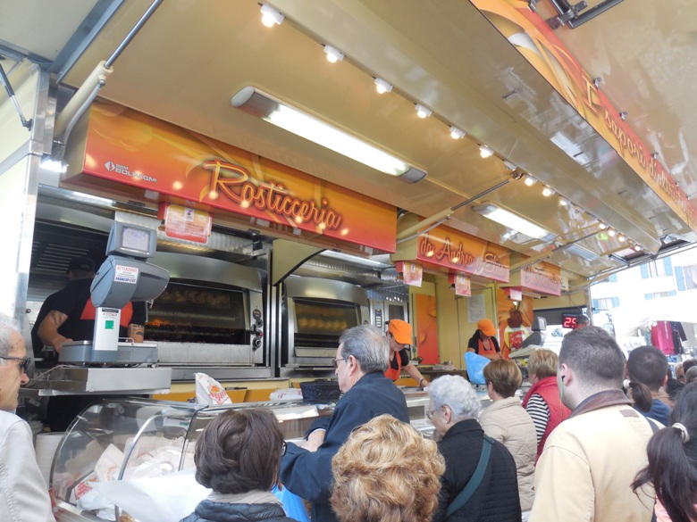 Locals line up for rotisserie chicken at the Thursday market in Mantova