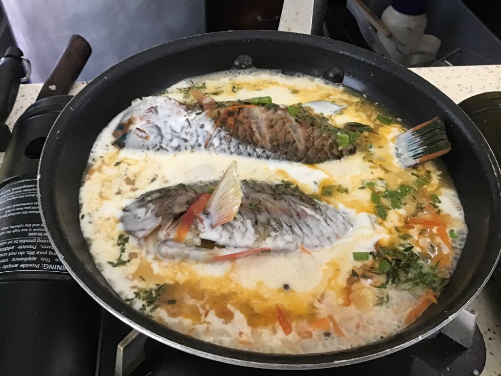 The fish finishing up in the pan of Jamaican curry sauce