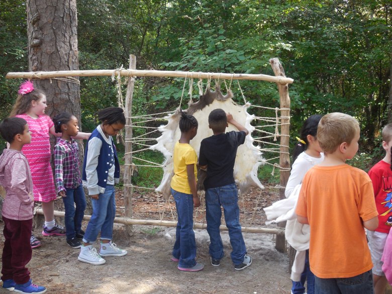 Kids scraping deer hide at Jamestown Settlement