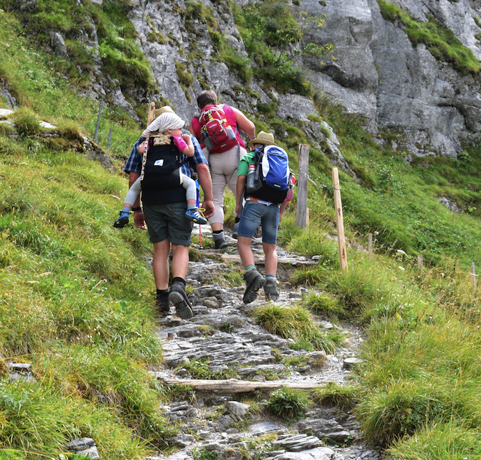 Grandfather carrying granddaughter up the trail above Grindewald