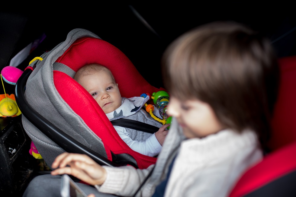 Little baby boy and his older brother, traveling in car seats, g