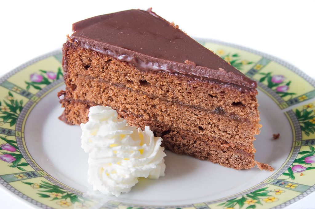 Slice of traditional austrian Sacher Torte cake with whipped cream