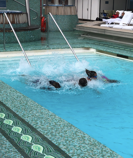 Kids having a fun day at sea in the top-deck pool of the Regent Seven Seas Mariner