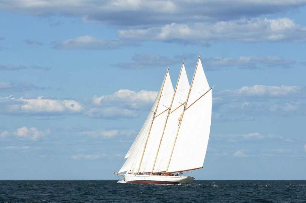 Authentic schooner windjamming sailing vessel with three masts cruises by on a warm summer day along the Maine Seacoast. Windjamming is a favorite attraction for tourists.