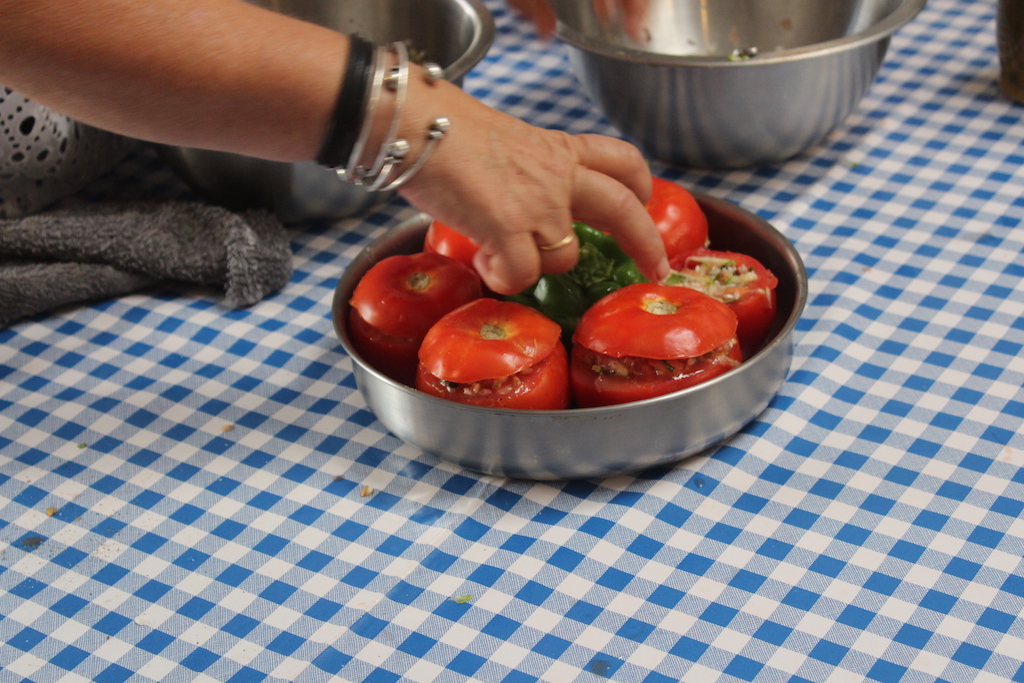 Preparing tomatoes and peppers stuffed with rice, garlic and mint