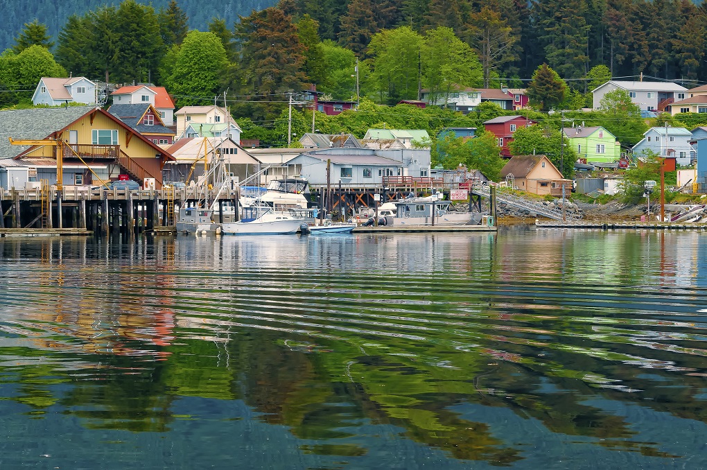Houses, buildings, and boats reflected on the water of Sitka, Alaska, an island community on the inside passage of coastal Alaska near the Pacific Ocean, and a cruise ship destination.