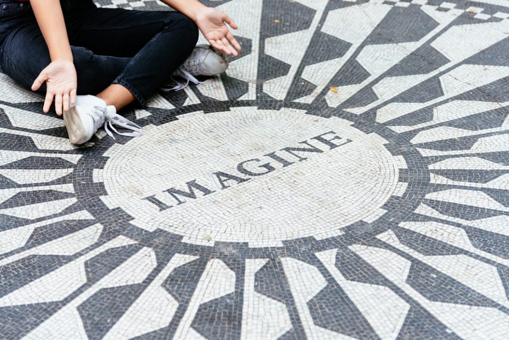 Young woman sitting on the Imagine mosaic in the Strawberry Fields in Central Park.