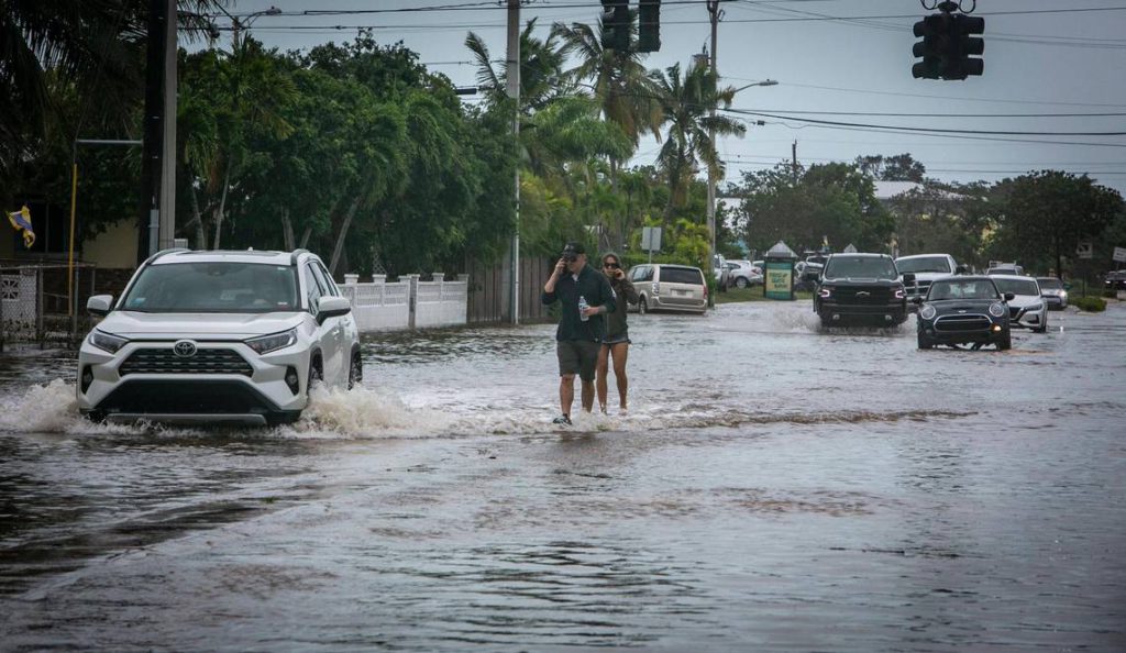 Key West, Florida, September 28, 2022 - People walk on the median surrounded by flood waters on Flagler Avenue in Key West. Hurricane Ian brushed Key West on its way to the mainland leaving flooded streets due to rain and storm surge.