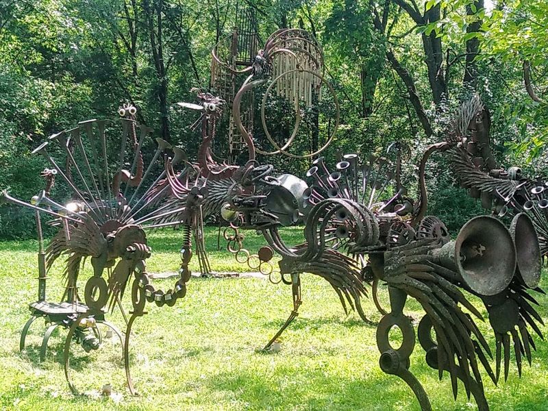 Surrounded By Dozens Of Whimsical Scrap Metal Sculptures