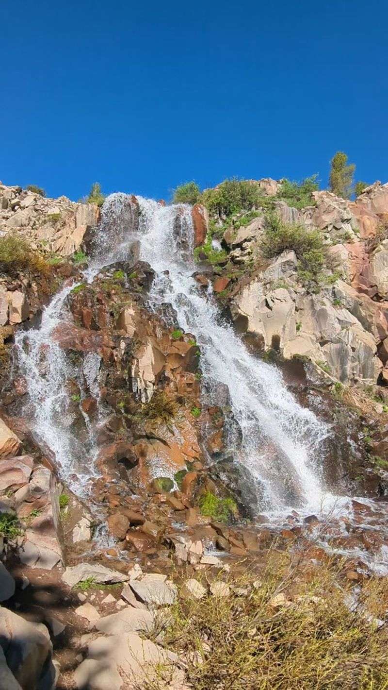 The Waterfall Spreads Across A Wide Red Rock Face