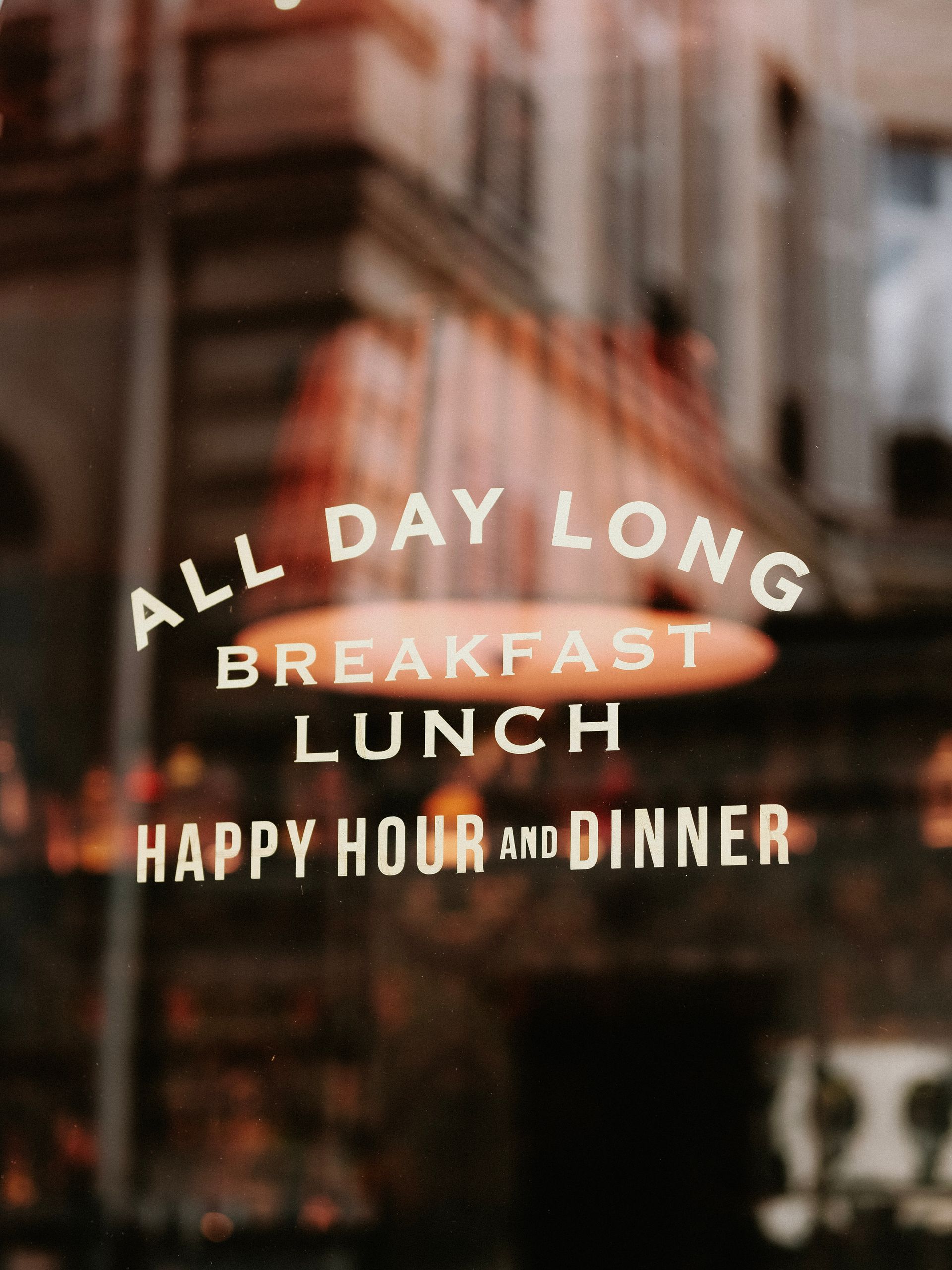 Reflective window with text advertising dining options at a restaurant.