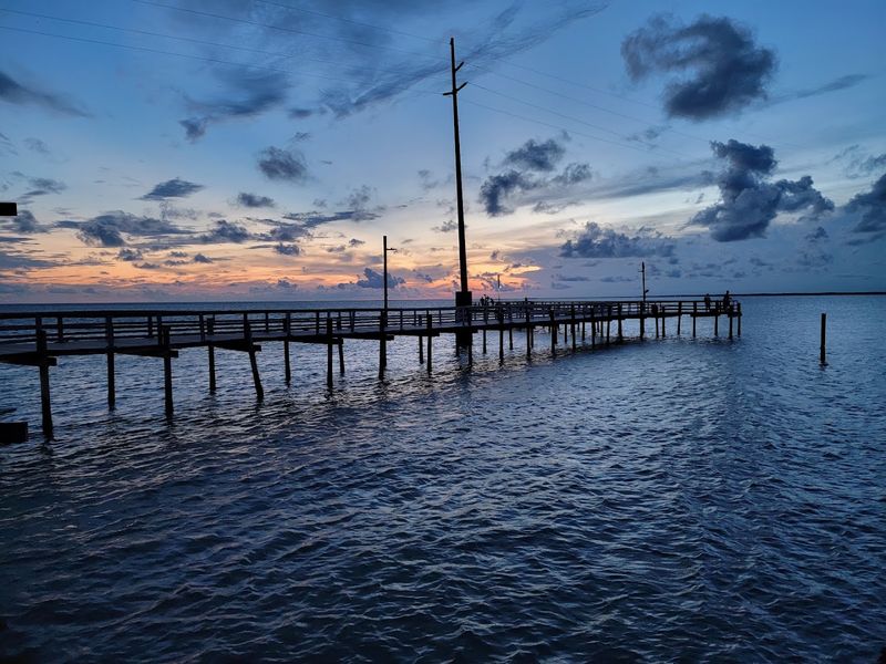 An Old Fishing Pier Now Stands On Dry Land Beside The Shifting Shoreline