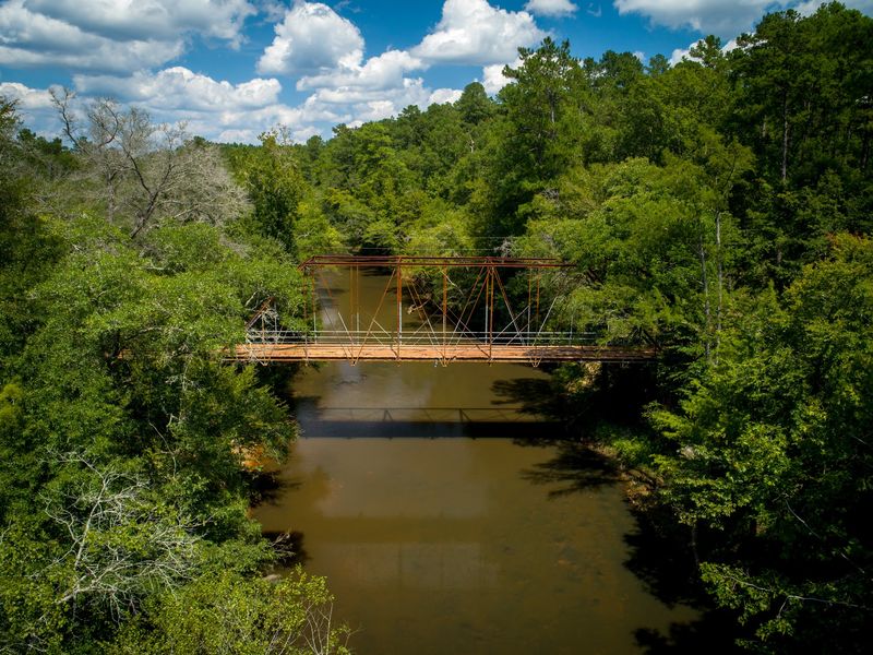 A Century Of Whispers Above Slow Brown Water