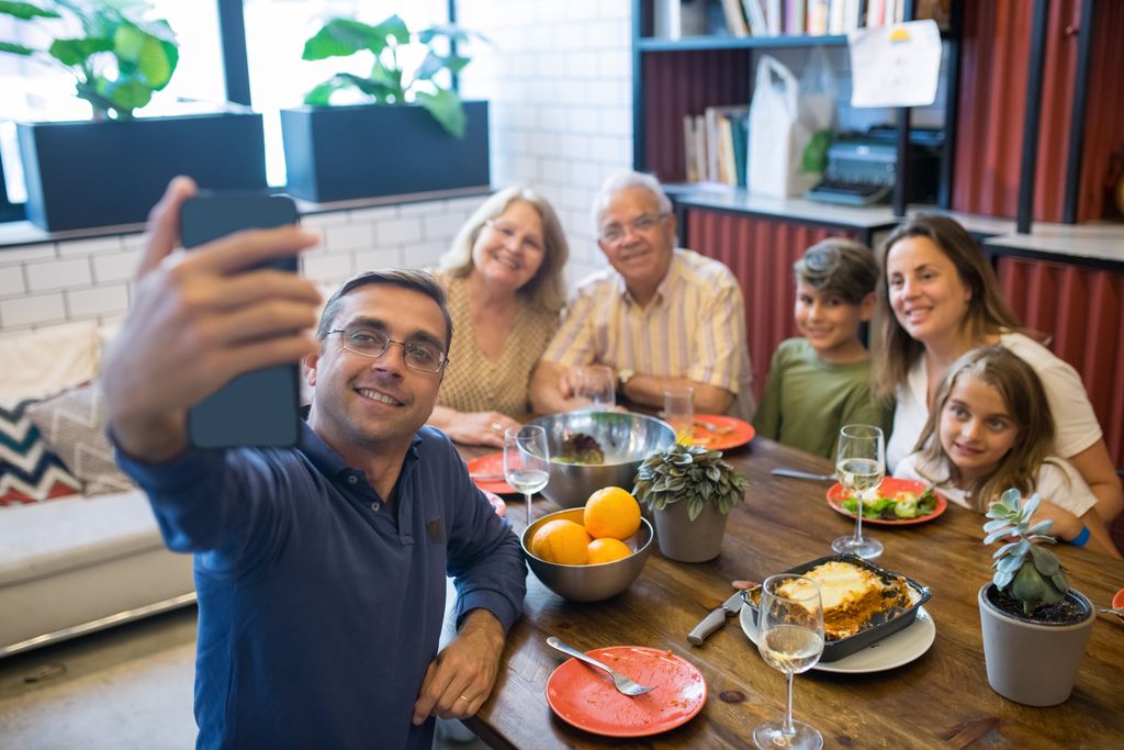 Happy family taking a selfie while enjoying lunch together at a cozy home setting.